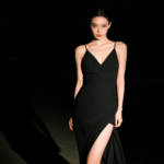 Elegant woman in black dress with thigh-high slit.