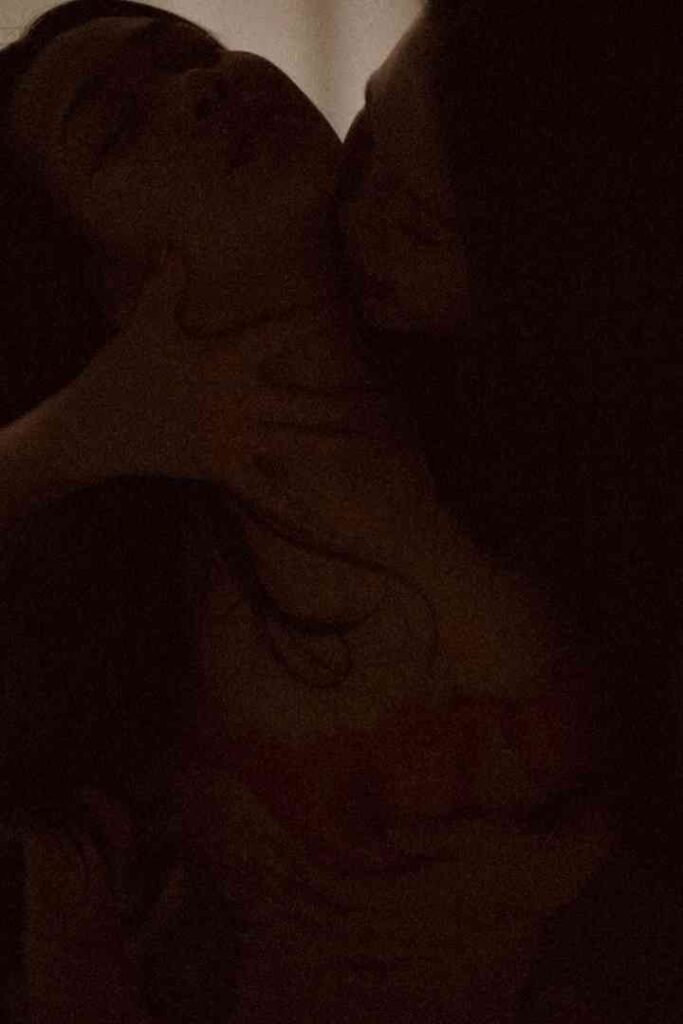 Viola and Cici share an intimate moment, embracing closely in dim lighting.